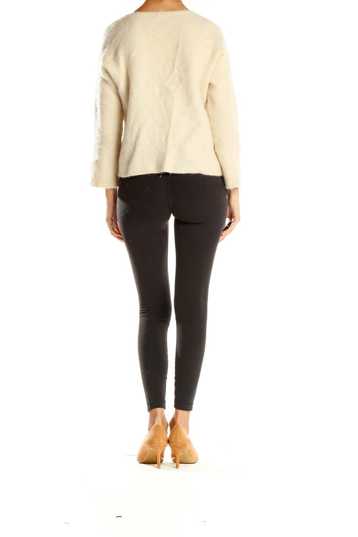 Side view of Eileen Fisher cream fuzzy knit V-neck sweater with black leggings