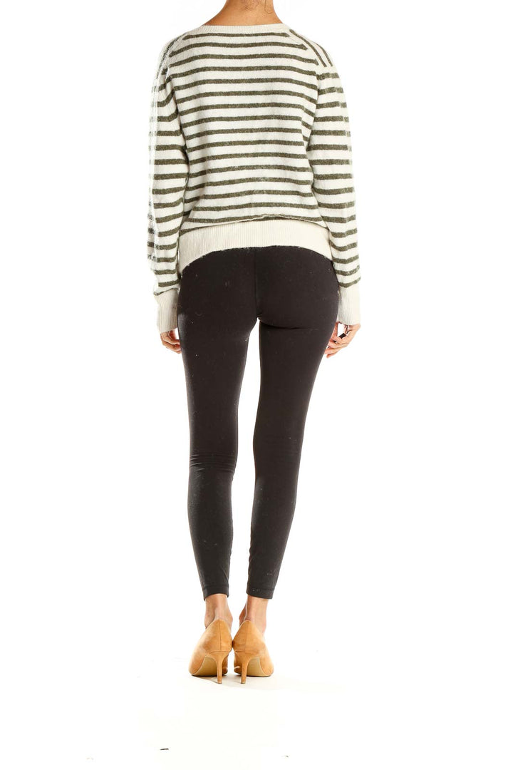 Side view of model wearing Madewell white and gray striped V-neck sweater with black leggings