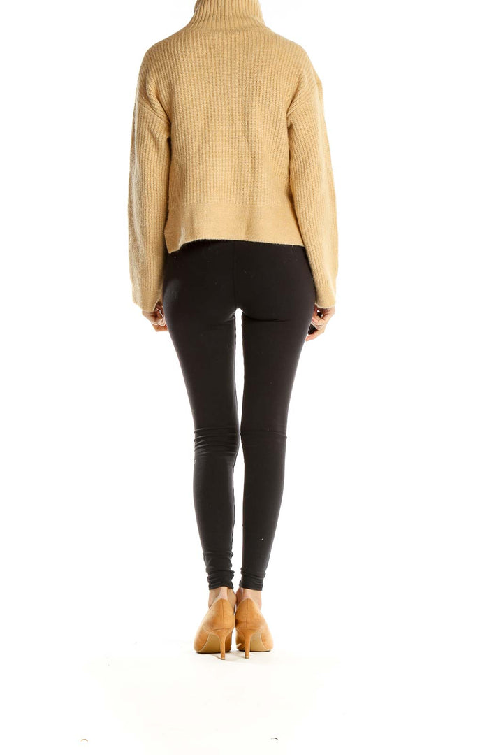 Side view of model wearing Topshop beige ribbed turtleneck cropped sweater with black leggings