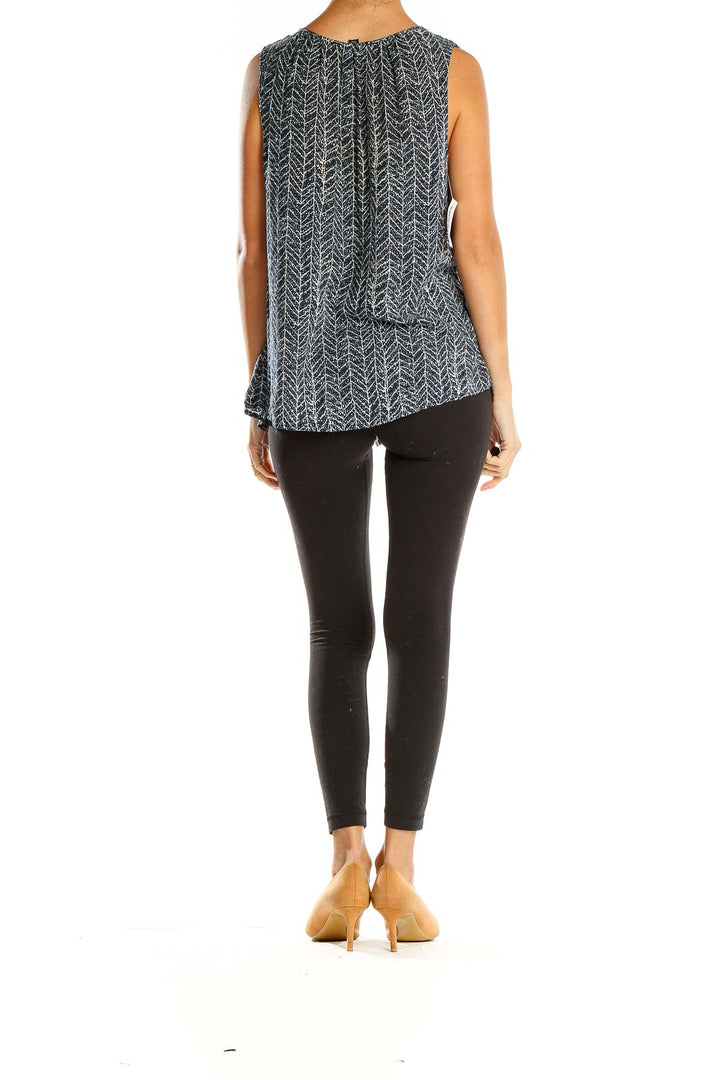 Side view of model wearing Willi Smith black herringbone print sleeveless blouse with black leggings