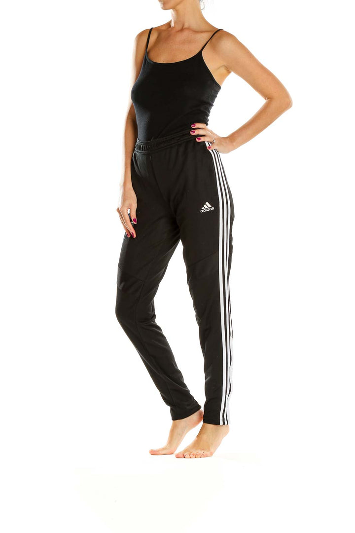 Front view of black Adidas track pants with white stripes