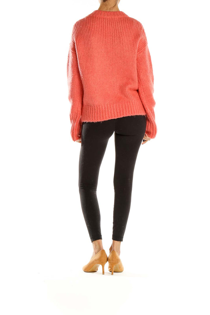 Side view of coral chunky knit sweater by Sanctuary with black leggings