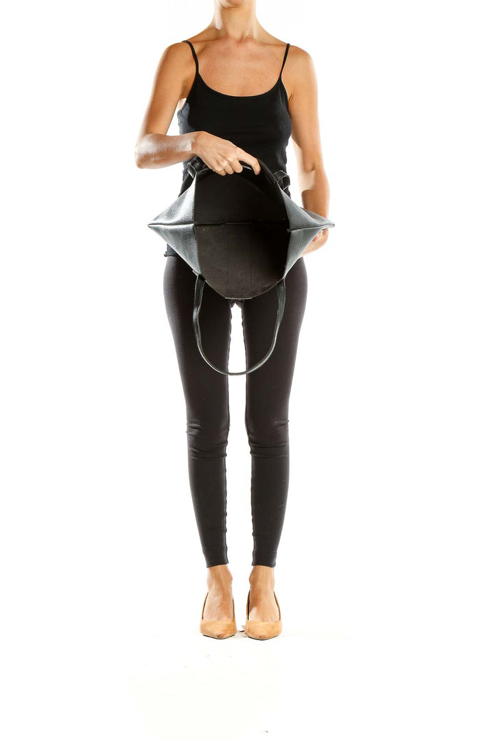 Woman carrying Vince Camuto black leather tote bag, showcasing its size and style