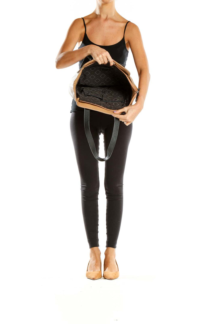 Side view of woman carrying Nine West tan leather tote bag with black accents
