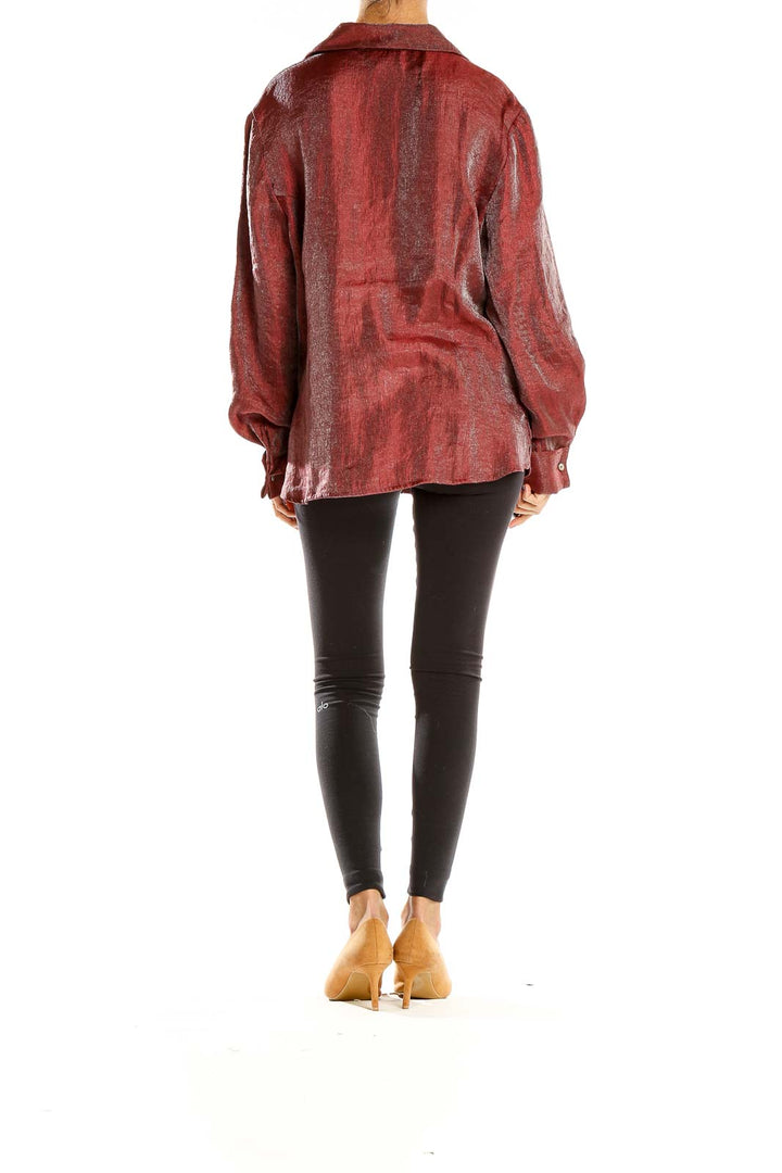 Side view of model wearing burgundy shimmering button-down blouse with black pants