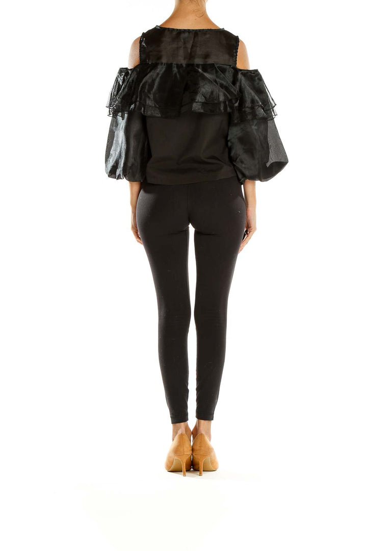 Side view of black ruffled cold-shoulder top by Twist x Turn with model