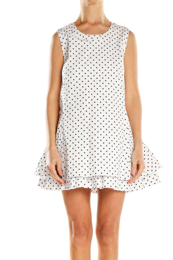 Front view of white polka dot sleeveless mini dress with ruffle hem
