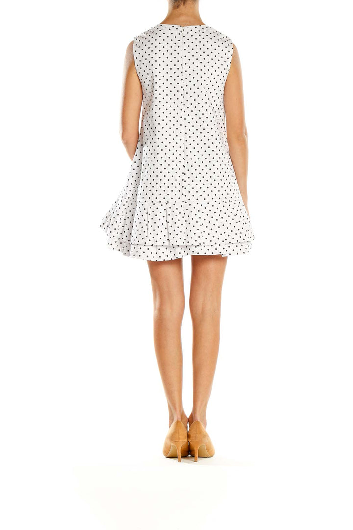 Side view of white polka dot sleeveless mini dress showing A-line silhouette