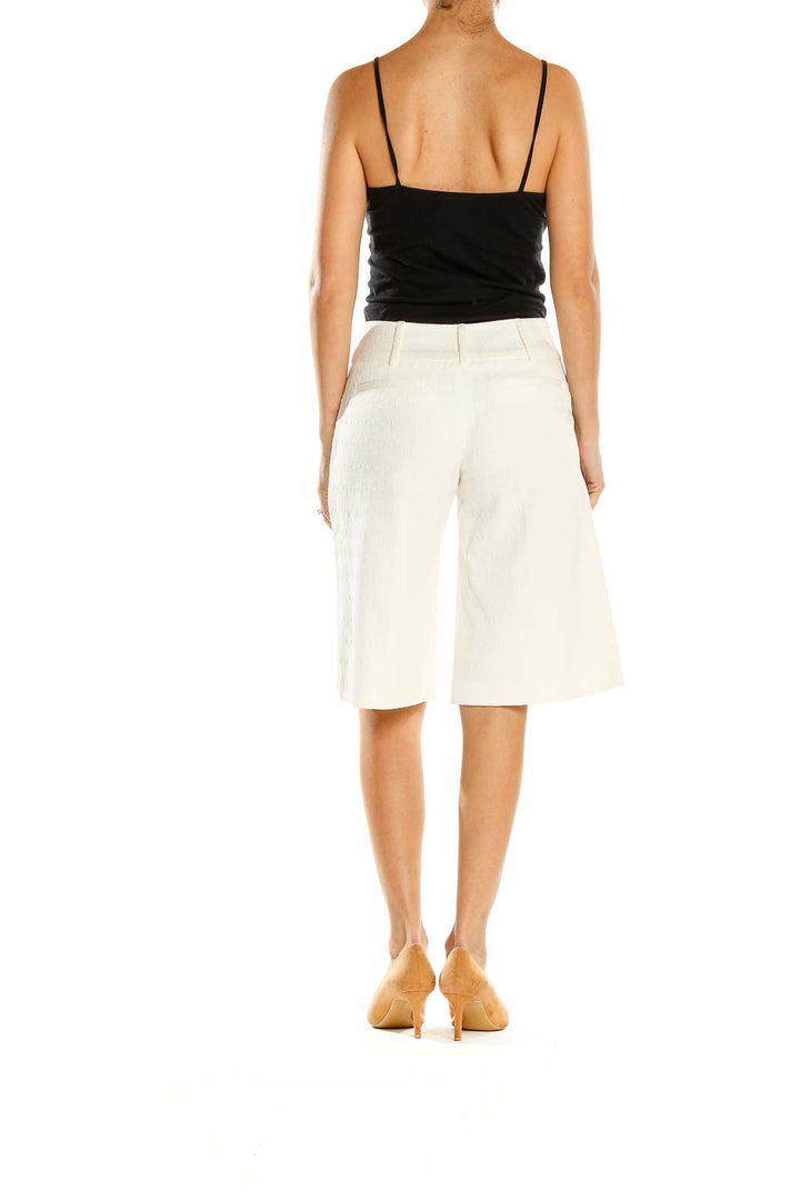 Side view of Milly white tailored Bermuda shorts on model with black top
