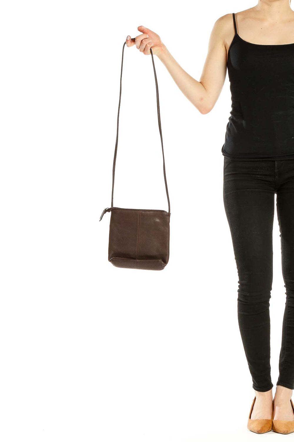 Front view of Stone Mountain brown leather crossbody bag held by hand