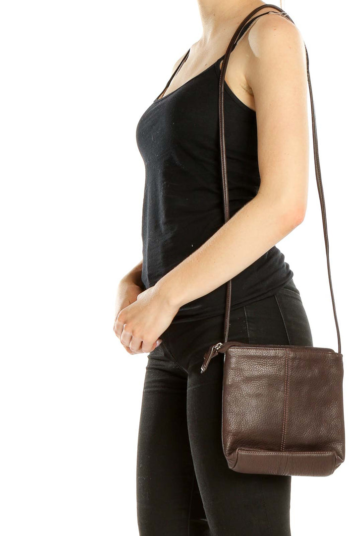 Front view of Stone Mountain brown leather crossbody bag held by hand