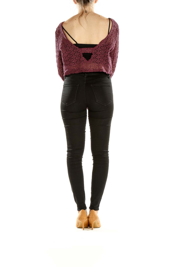 Side view of model wearing burgundy crochet crop sweater with black pants