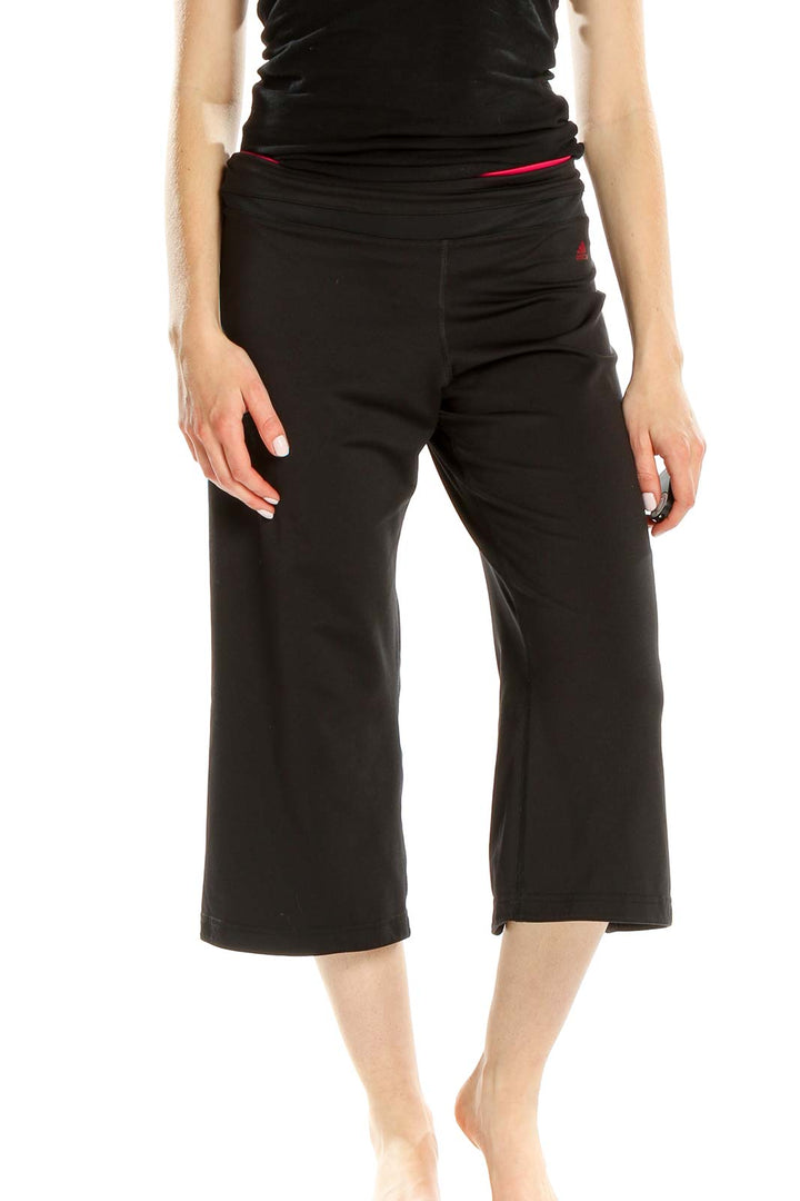 Front view of black Adidas capri yoga pants with red waistband accent