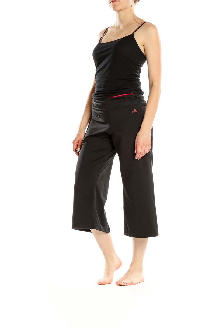 Front view of black Adidas capri yoga pants with red waistband accent