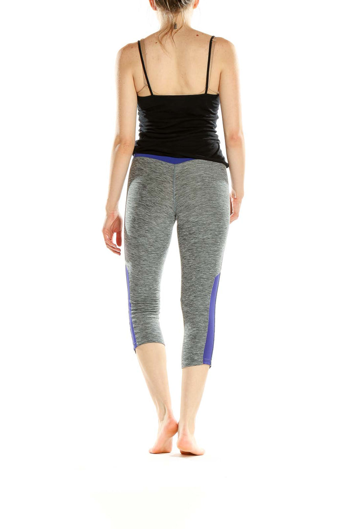 Side view of gray heathered New Balance capri leggings with blue side panels