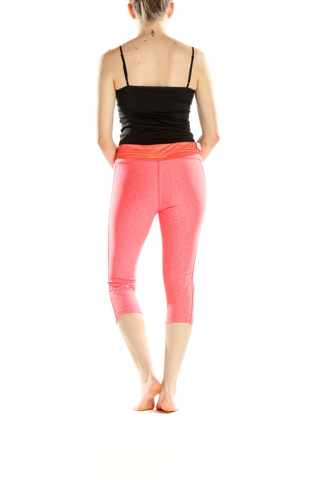 Side view of pink Under Armour capri workout leggings on model