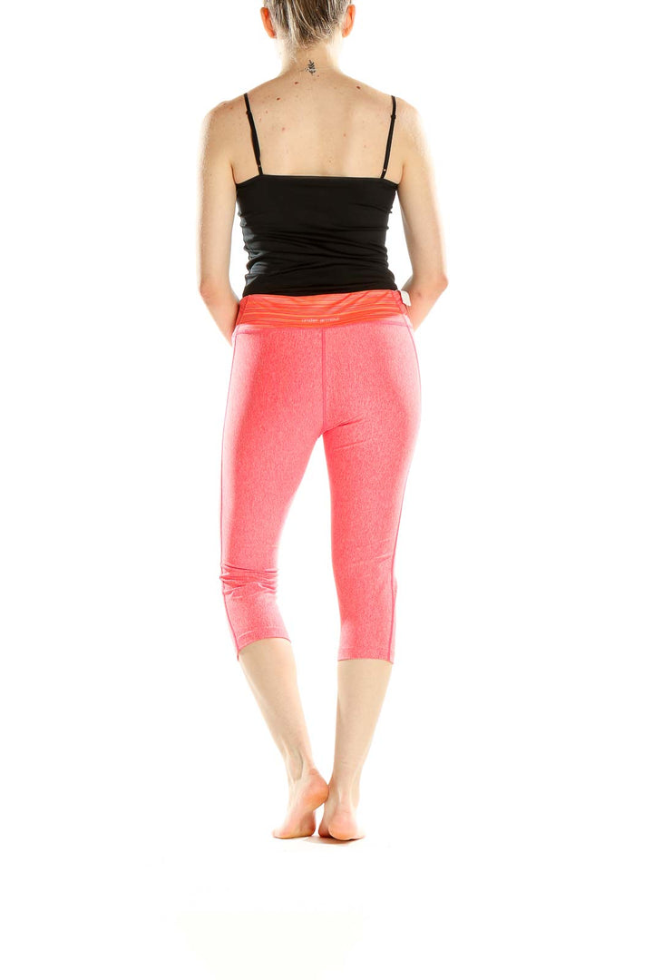 Side view of pink Under Armour capri workout leggings on model