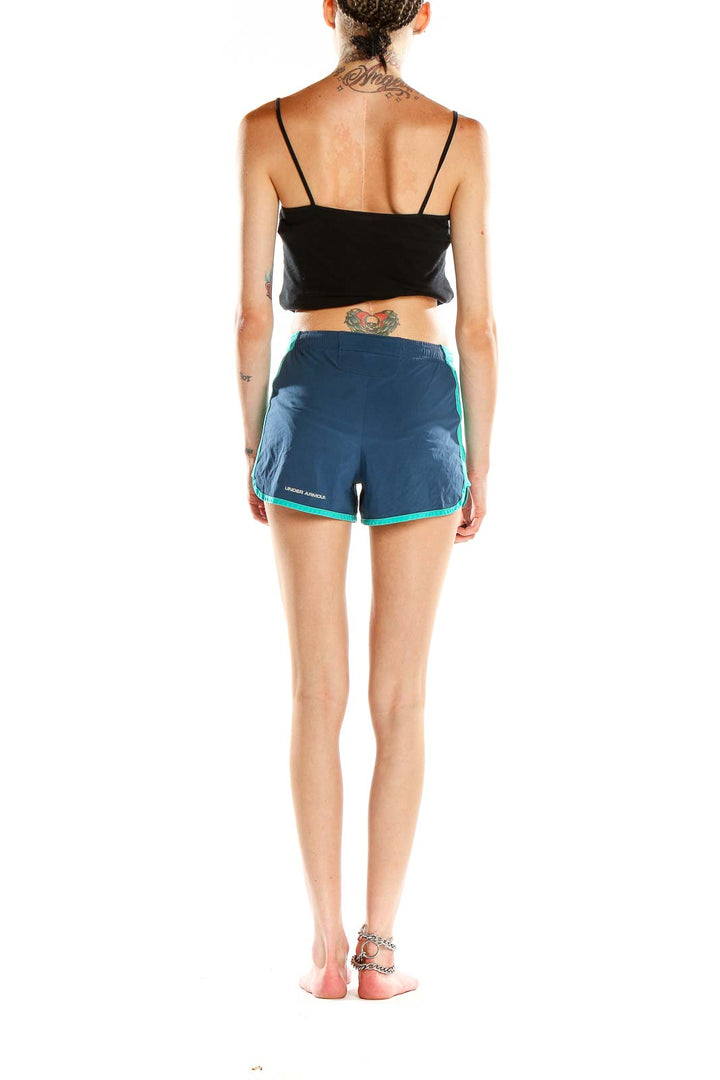 Side view of woman wearing Under Armour navy and teal athletic shorts