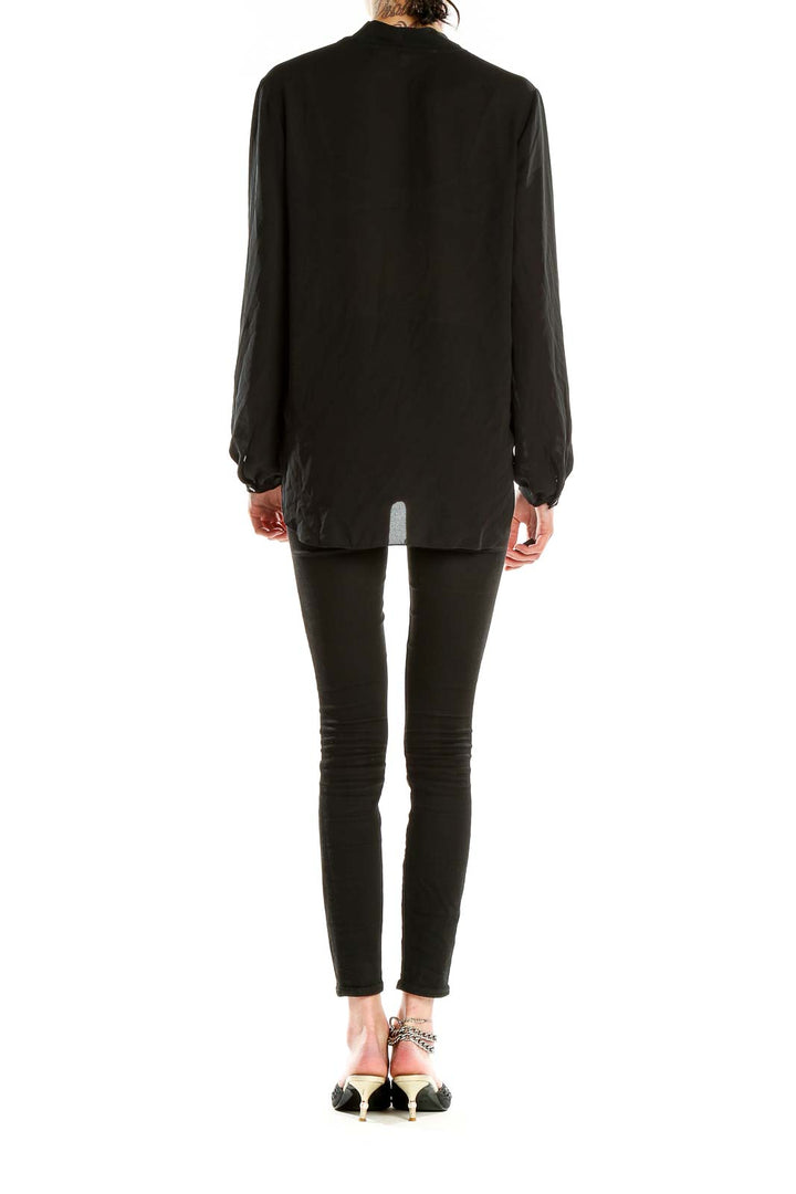 Side view of Max Studio black wrap blouse on model with skinny jeans