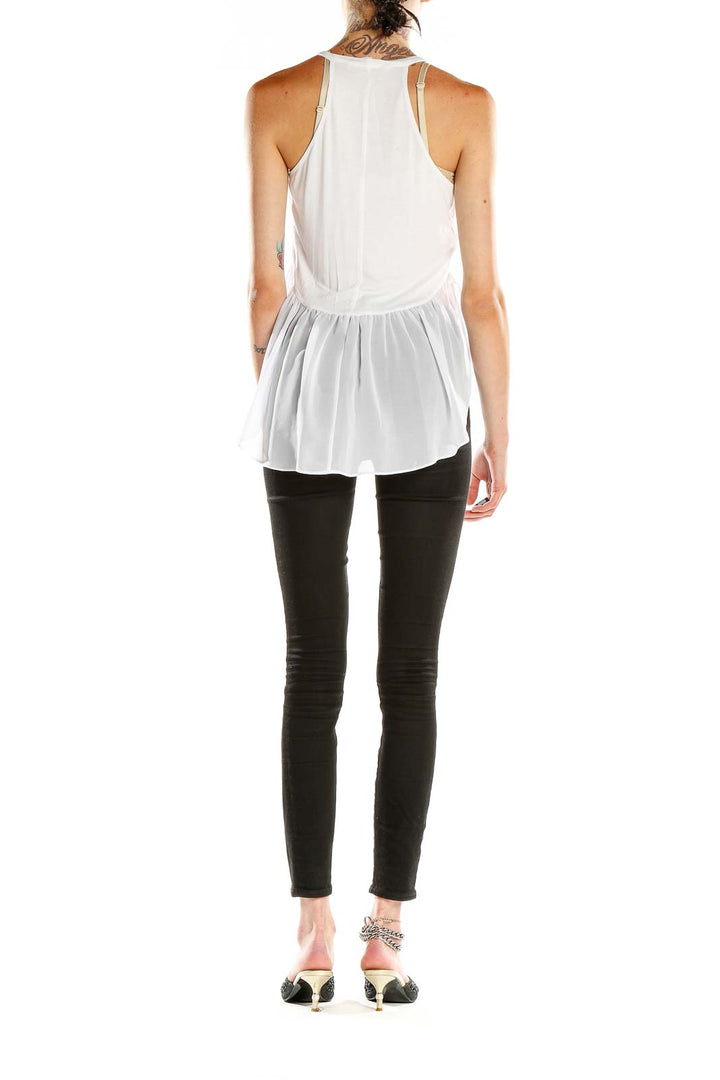 Side view of BCBGeneration white peplum tank top showing sheer hem