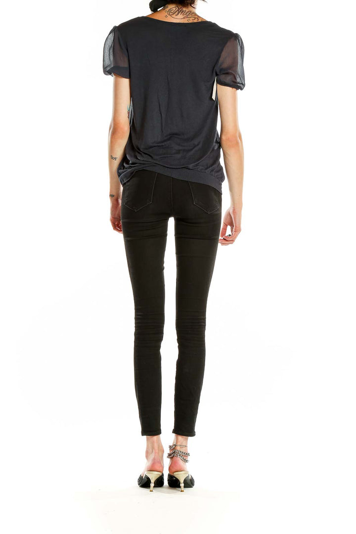 Side view of Cynthia Rowley black top showing elasticated waistband and sheer sleeves