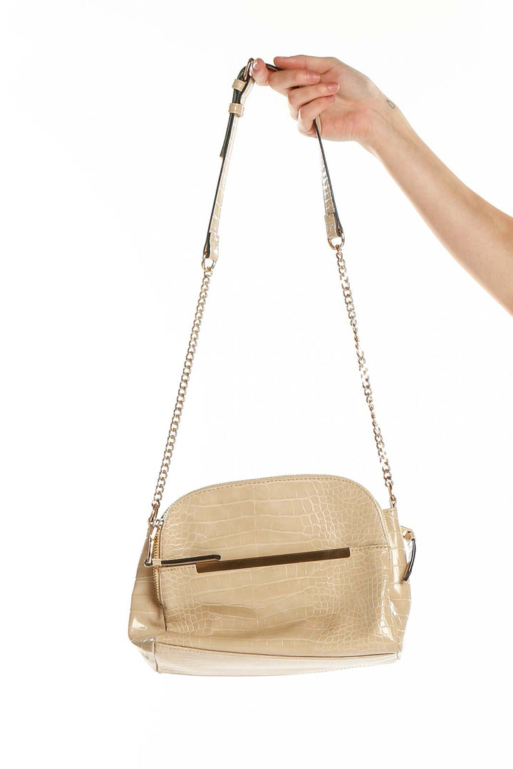 Front view of beige croc-embossed crossbody bag with gold-tone accent