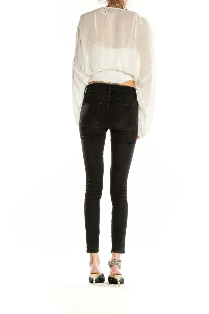Side view of Anthropologie white sheer cropped peasant blouse paired with black jeans