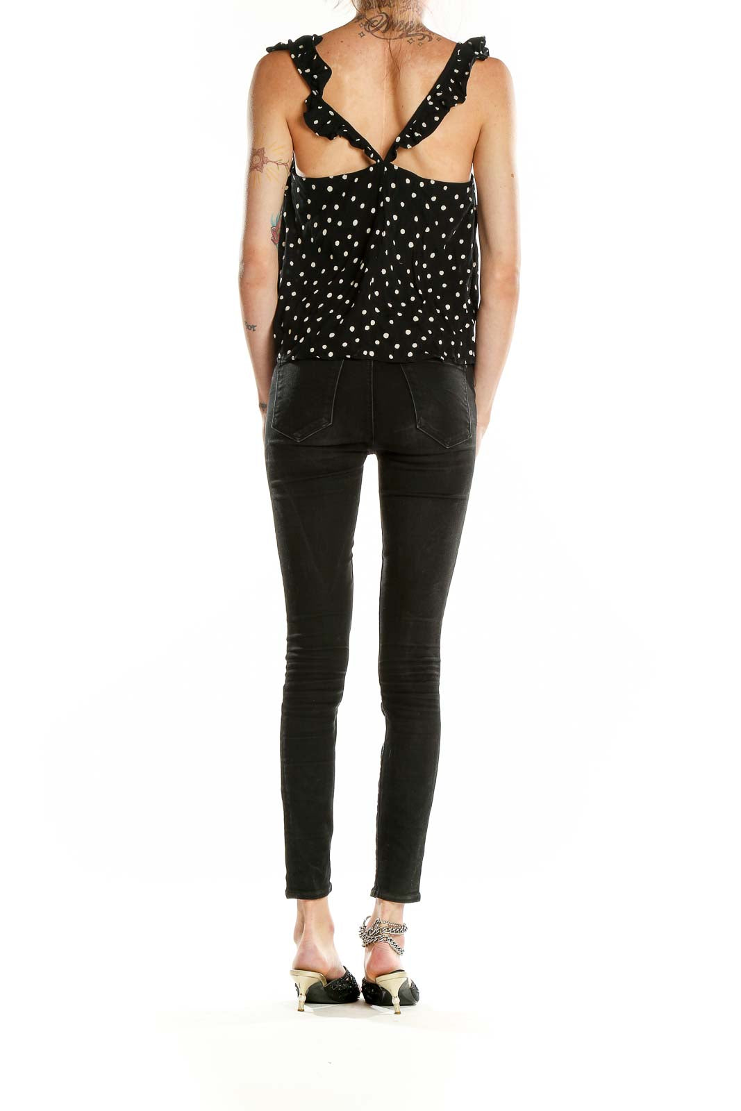 Side view of model wearing Madewell black polka dot tank top with black jeans