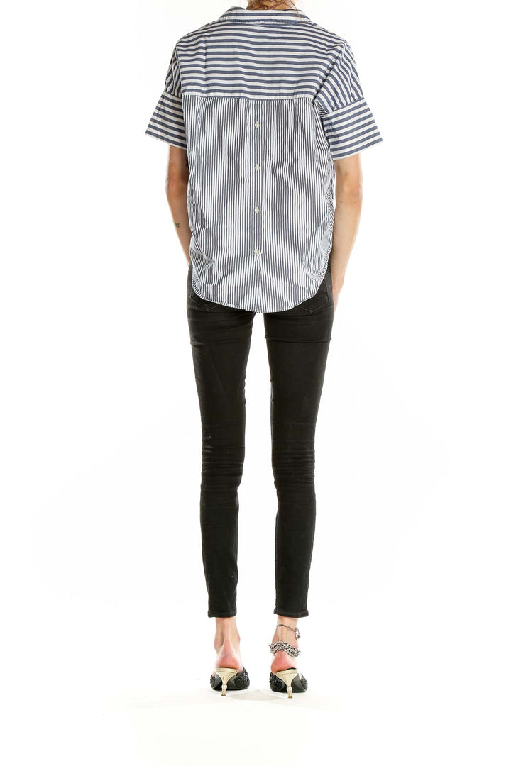 Side view of model wearing Madewell blue and white striped short-sleeve button-up shirt with black jeans