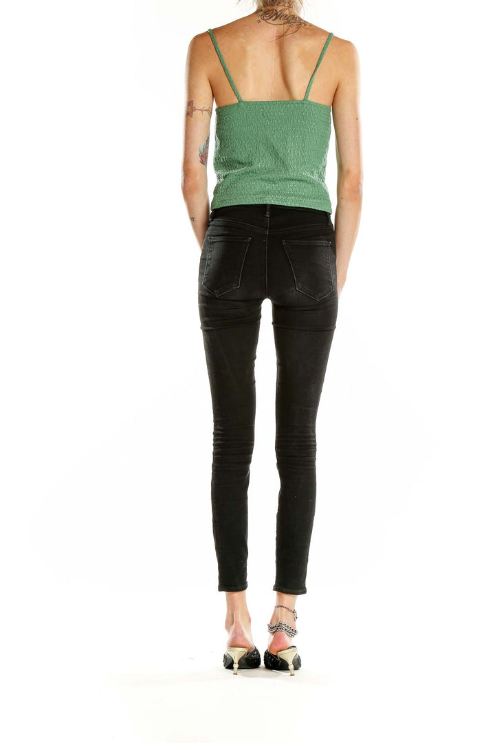 Side view of model wearing green textured cropped camisole top with black jeans