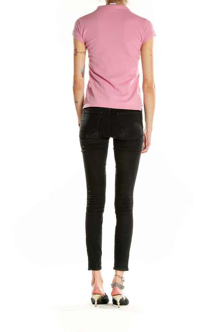 Side view of pink Lacoste polo shirt on model with black jeans