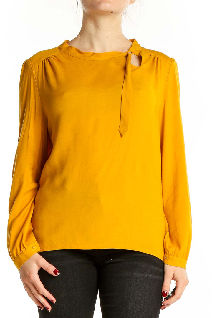 Front view of Anne Willi mustard long-sleeve blouse with tie neckline