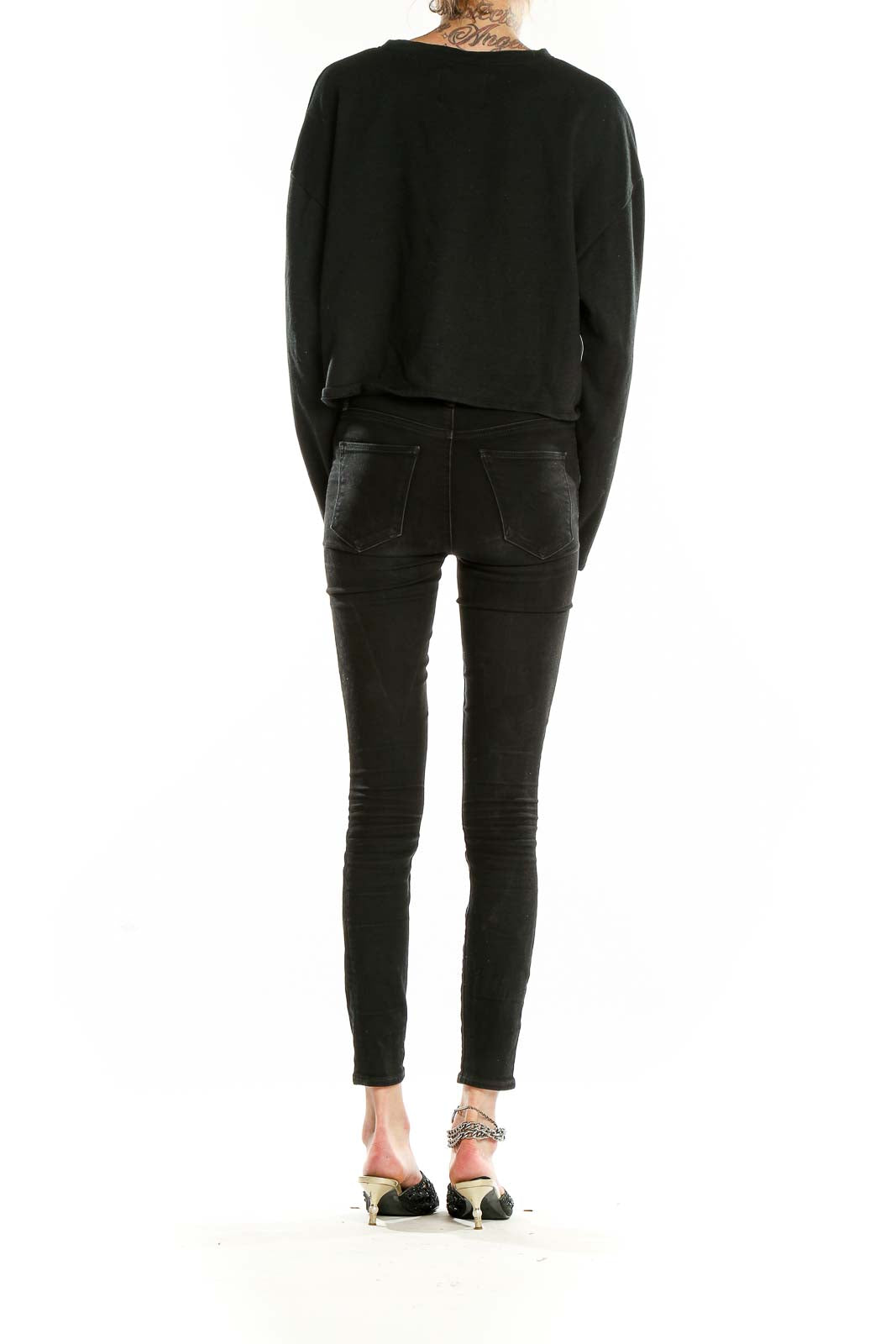 Back view of black Victoria Sport cropped long sleeve top on model with skinny jeans