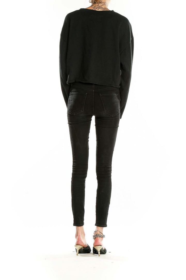 Back view of black Victoria Sport cropped long sleeve top on model with skinny jeans