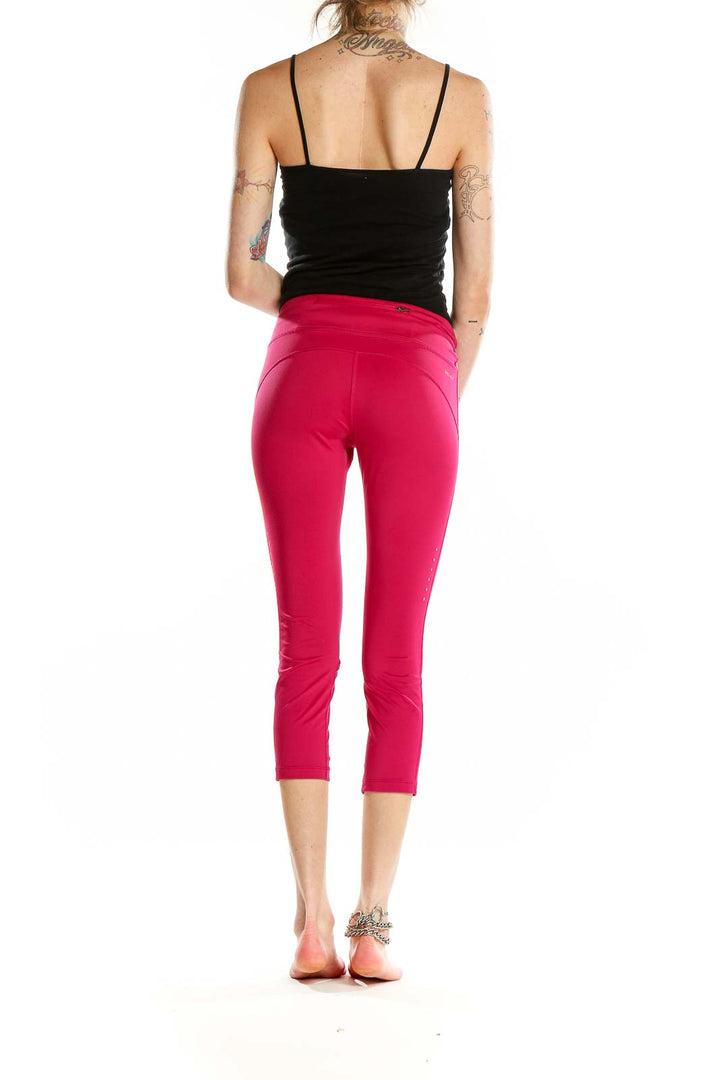 Back view of pink Nike cropped athletic leggings on model