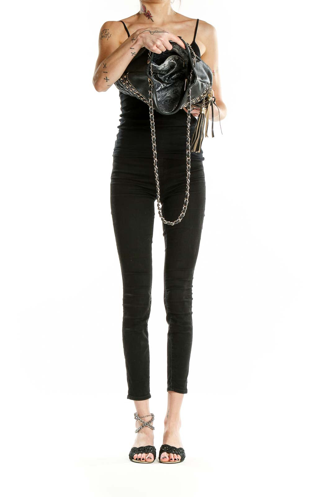Model wearing black quilted shoulder bag with gold studs and chain strap