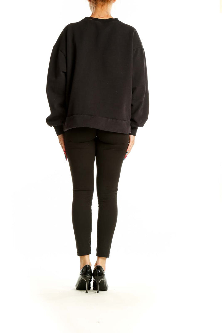 Back view of black oversized Athleta sweatshirt on model with leggings