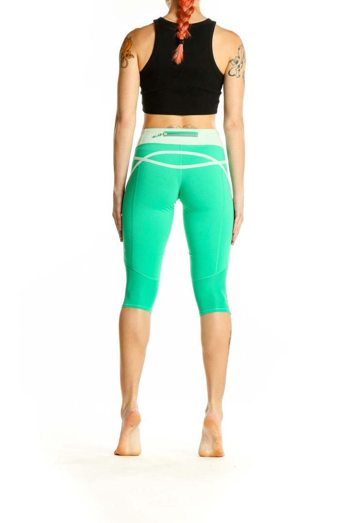 Side view of woman wearing green Lululemon capri leggings with black crop top