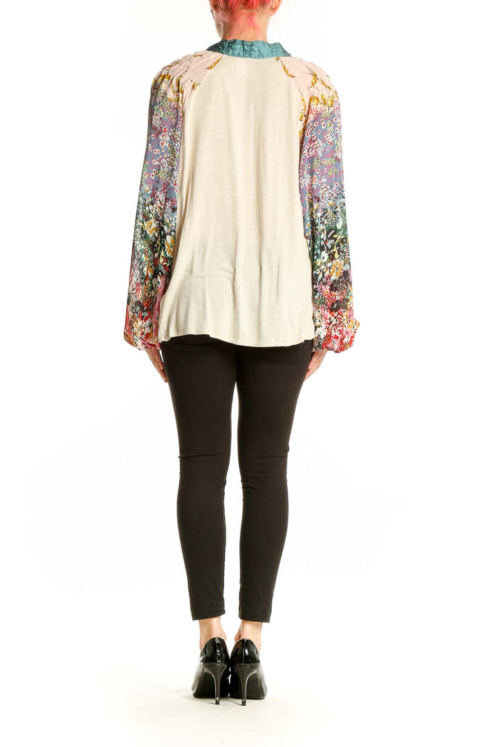 Back view of TINY beige peasant top showing floral print sleeves and relaxed fit
