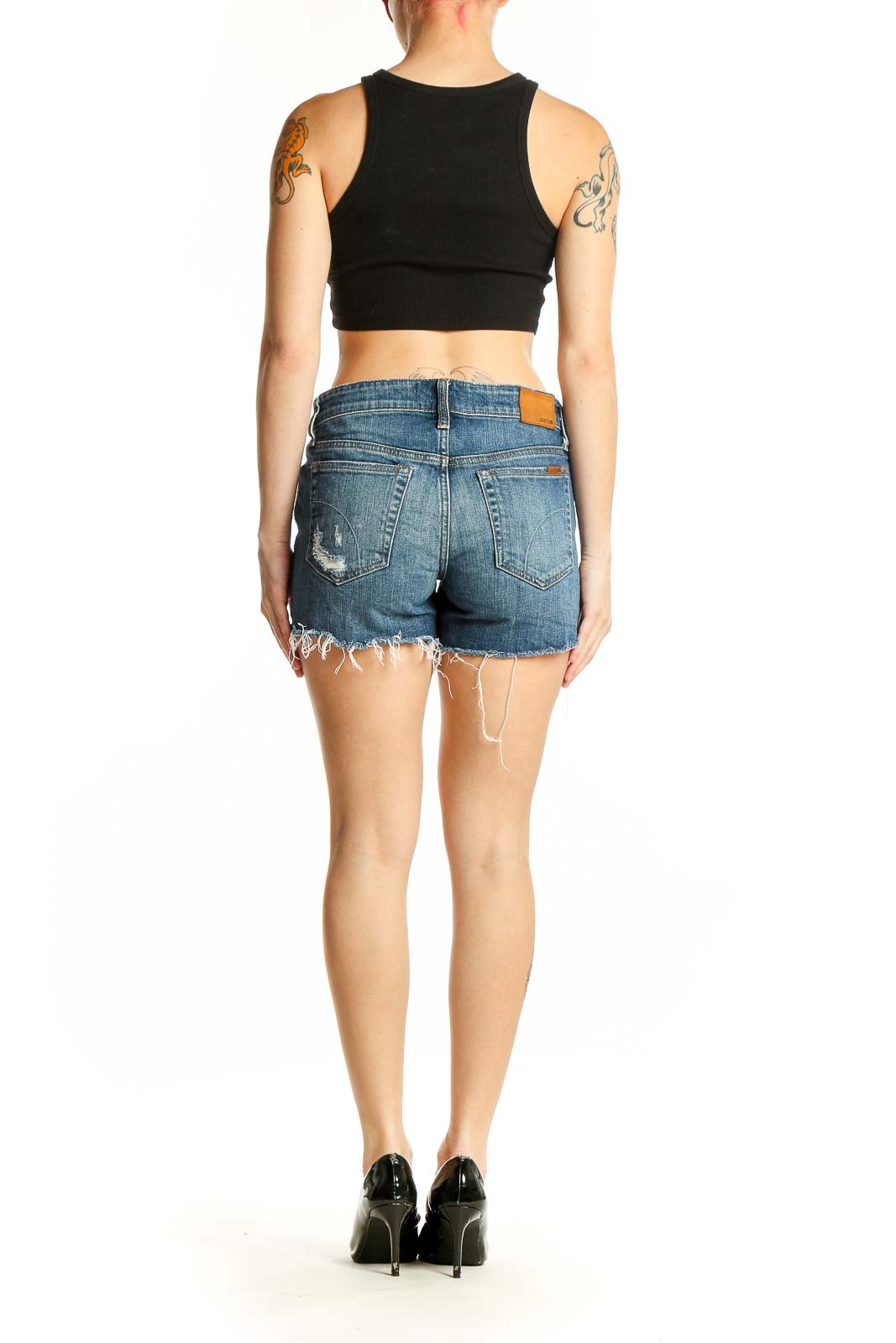Side view of woman wearing Joe's blue distressed denim cut-off shorts with black crop top