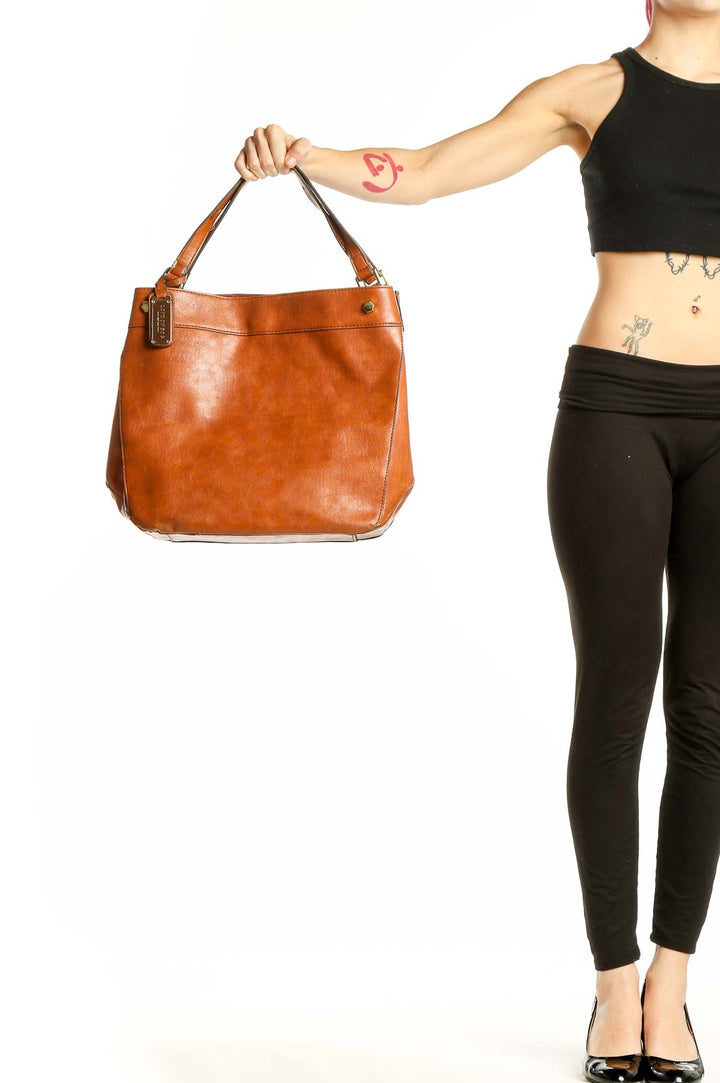 Front view of tan London Fog leather tote bag held by model's hand