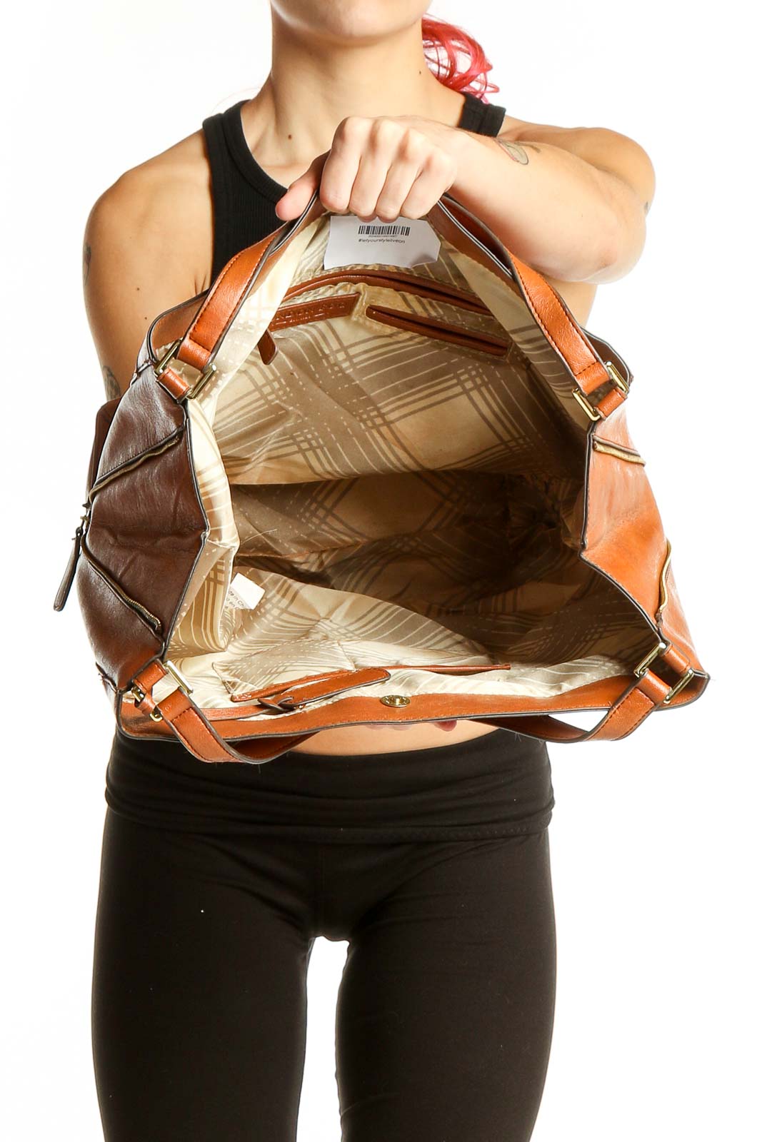 Side view of tan London Fog leather tote bag carried by model
