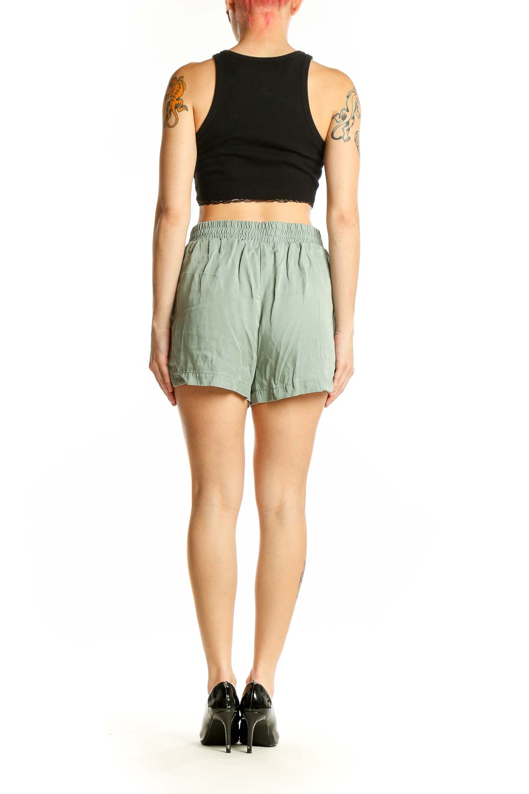 Side view of model wearing sage green Threads 4 Thought shorts with black top