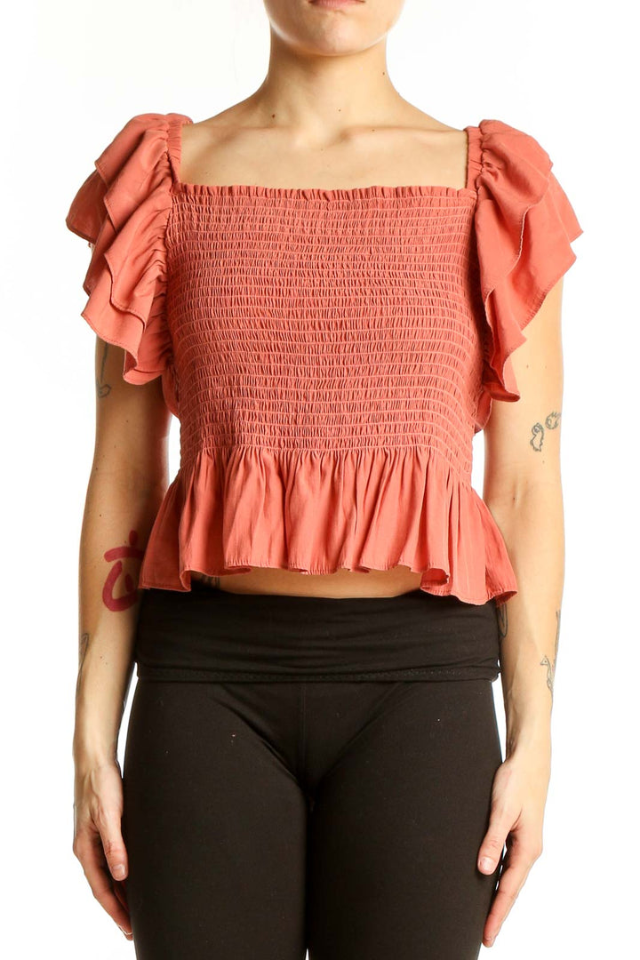 Front view of coral smocked crop top with ruffle sleeves