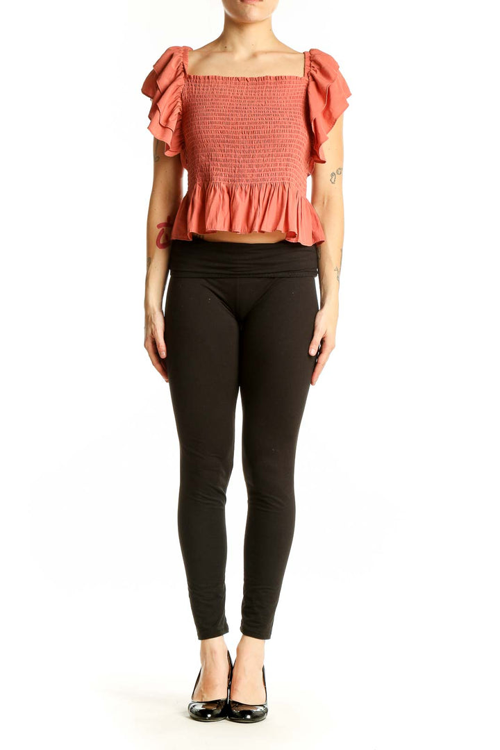 Front view of coral smocked crop top with ruffle sleeves