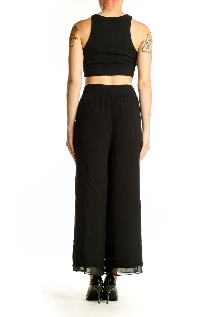 Side view of model wearing Theory black wide-leg pants with crop top