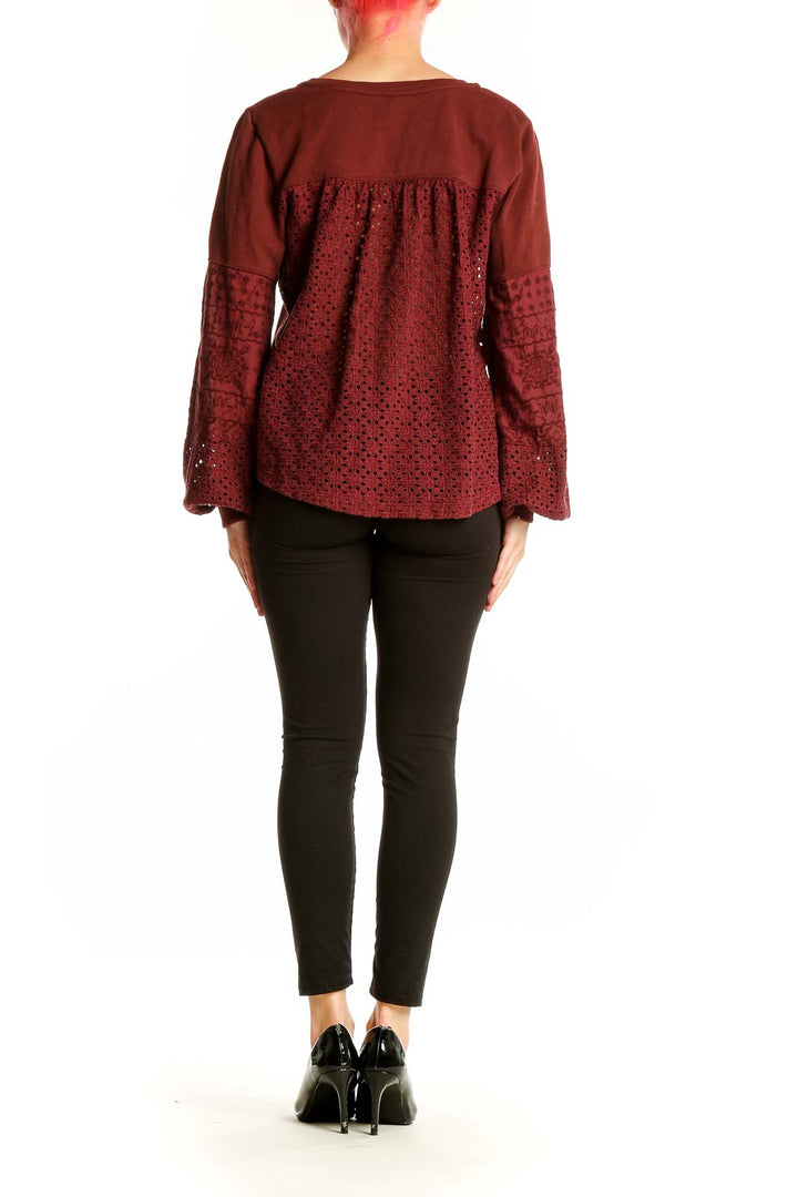 Side view of Anthropologie burgundy knit top showing embroidered bell sleeve detail