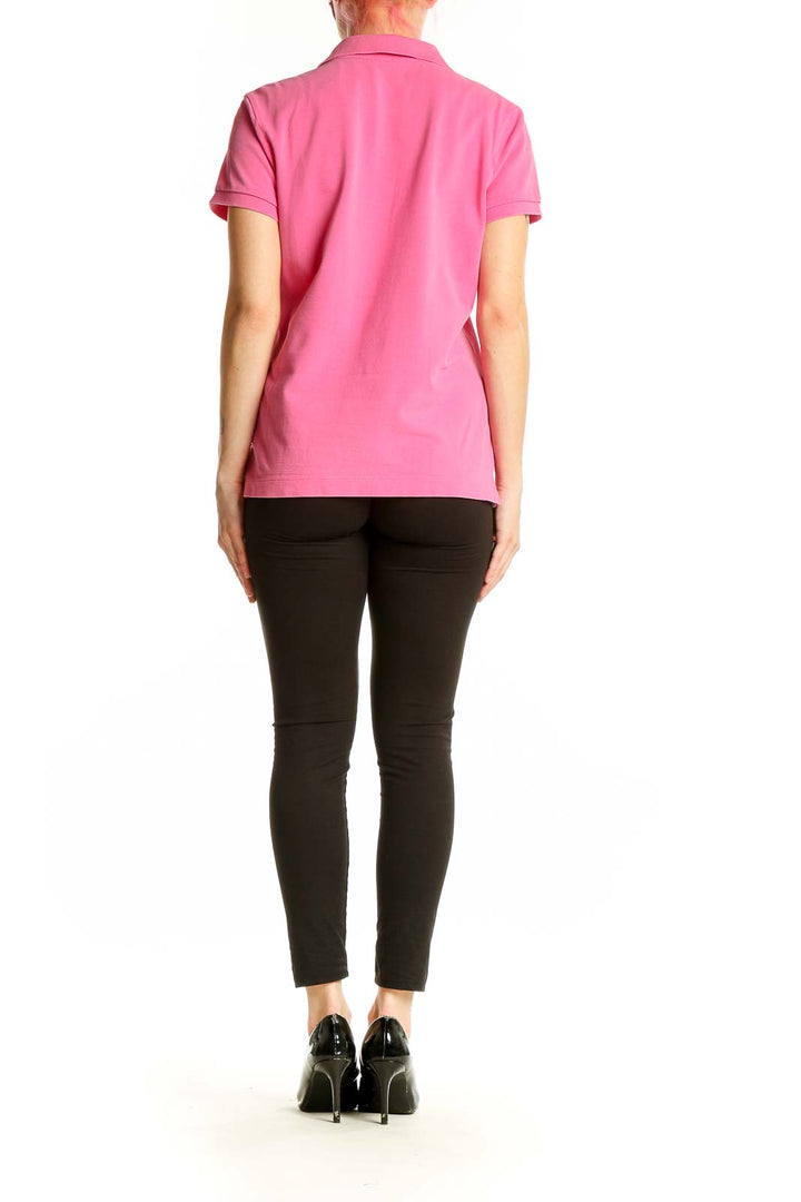 Side view of woman wearing pink Lilly Pulitzer cotton polo shirt with black pants
