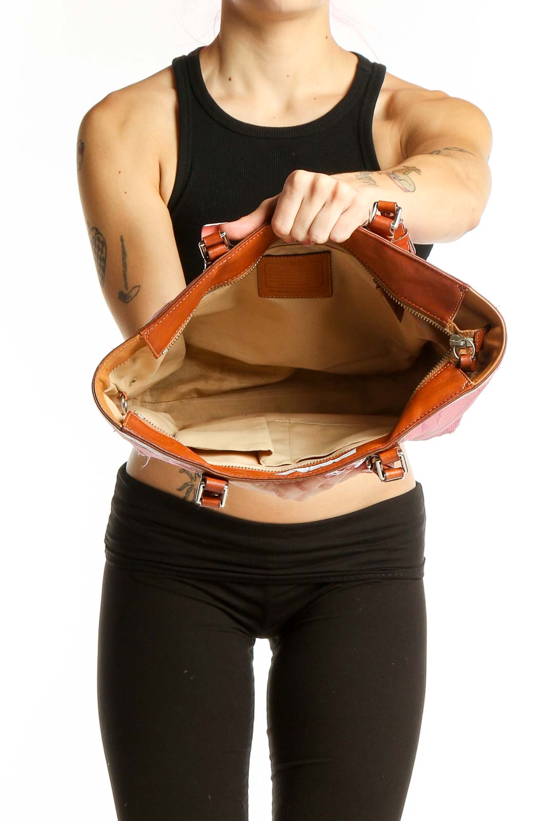 Woman carrying pink leather Coach tote bag on shoulder