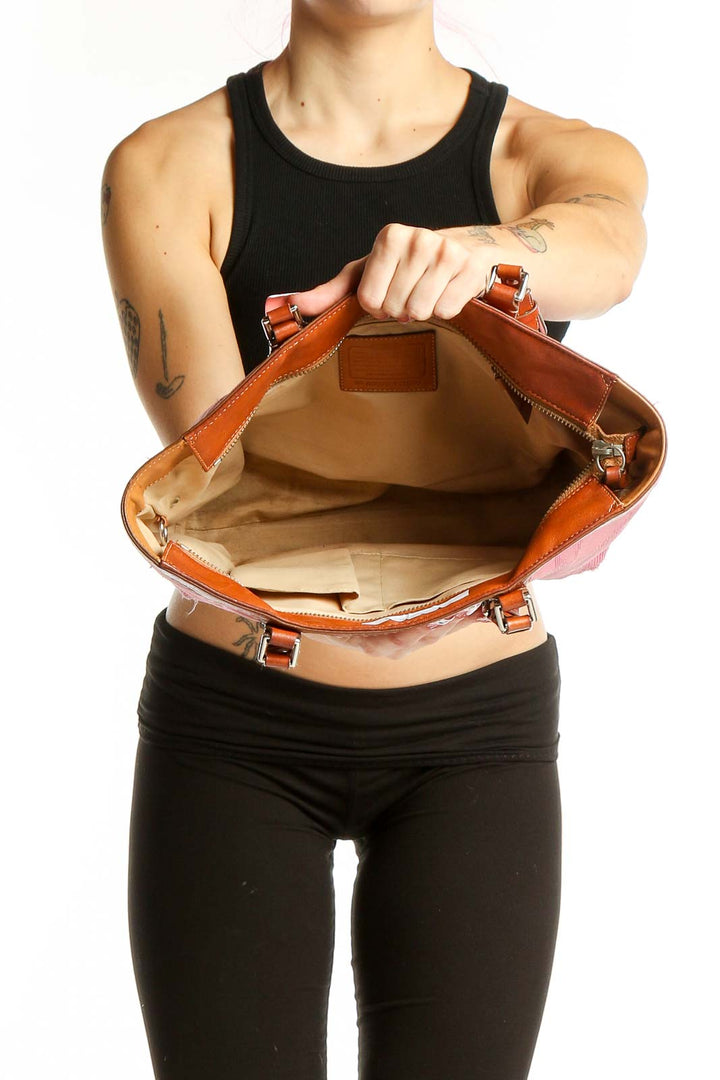 Woman carrying pink leather Coach tote bag on shoulder